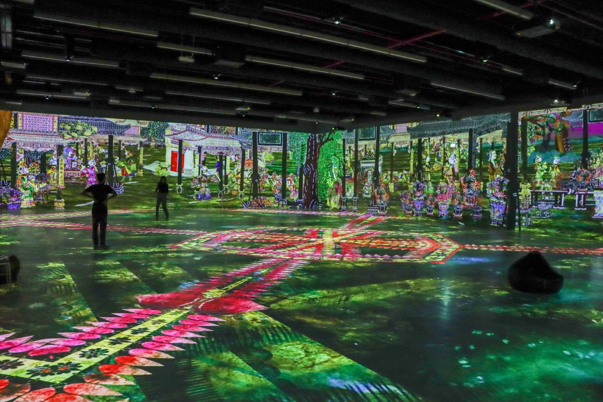 People standing inside ImmerSEE while a garden scene is projected across every wall and the floor
